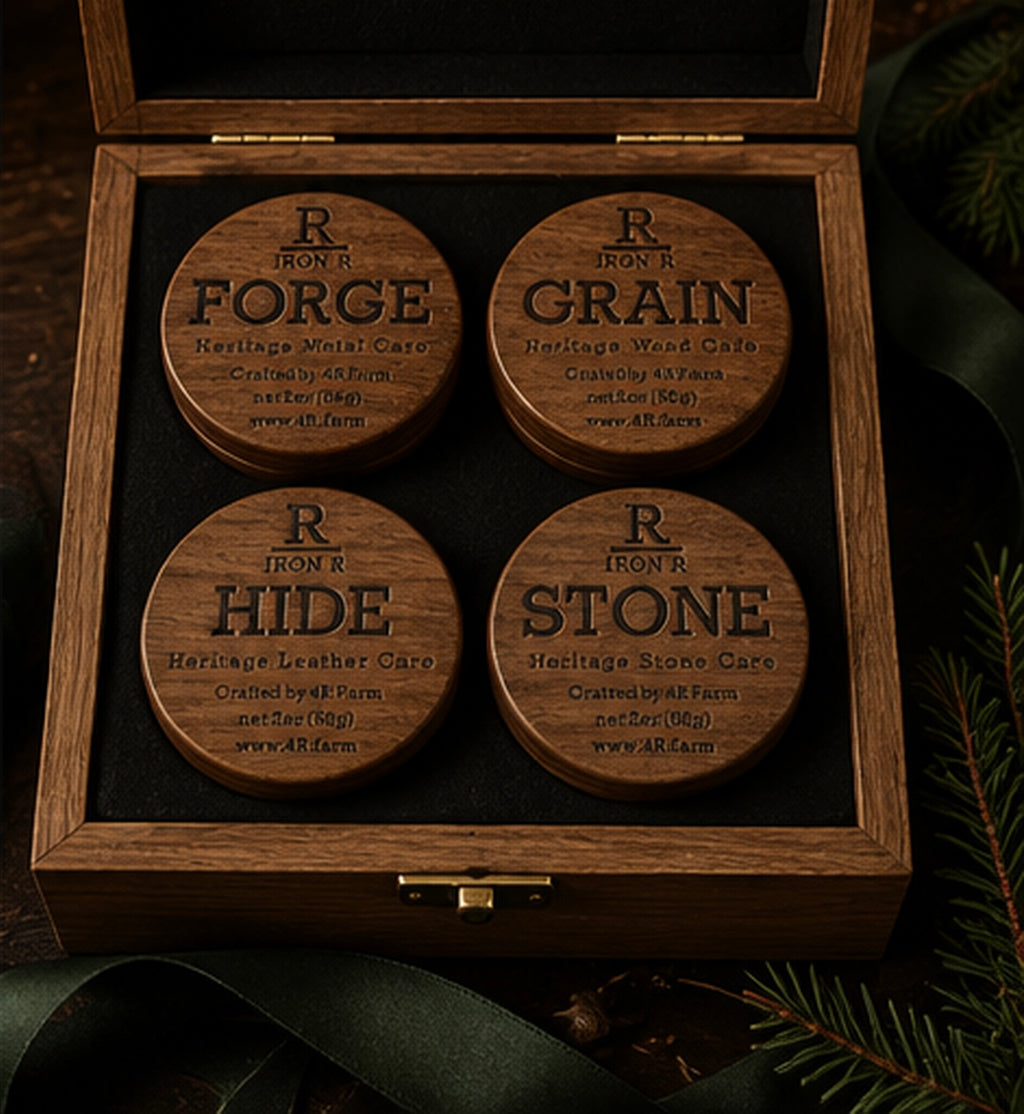 Open walnut gift box holding four IRON R care balms—FORGE, GRAIN, HIDE, and STONE—on black felt.