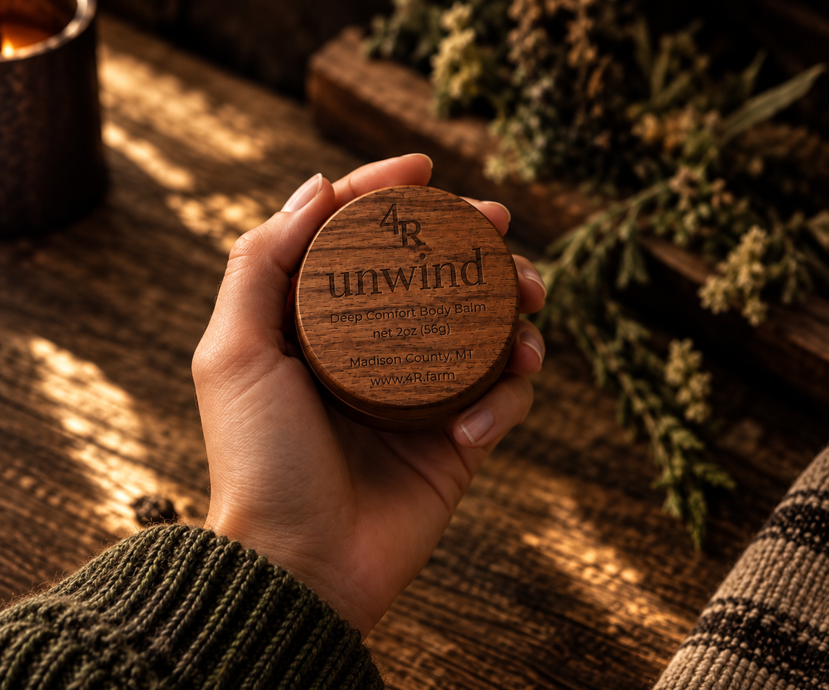 Hand holding UNWIND Deep Comfort Body Balm in its walnut container.