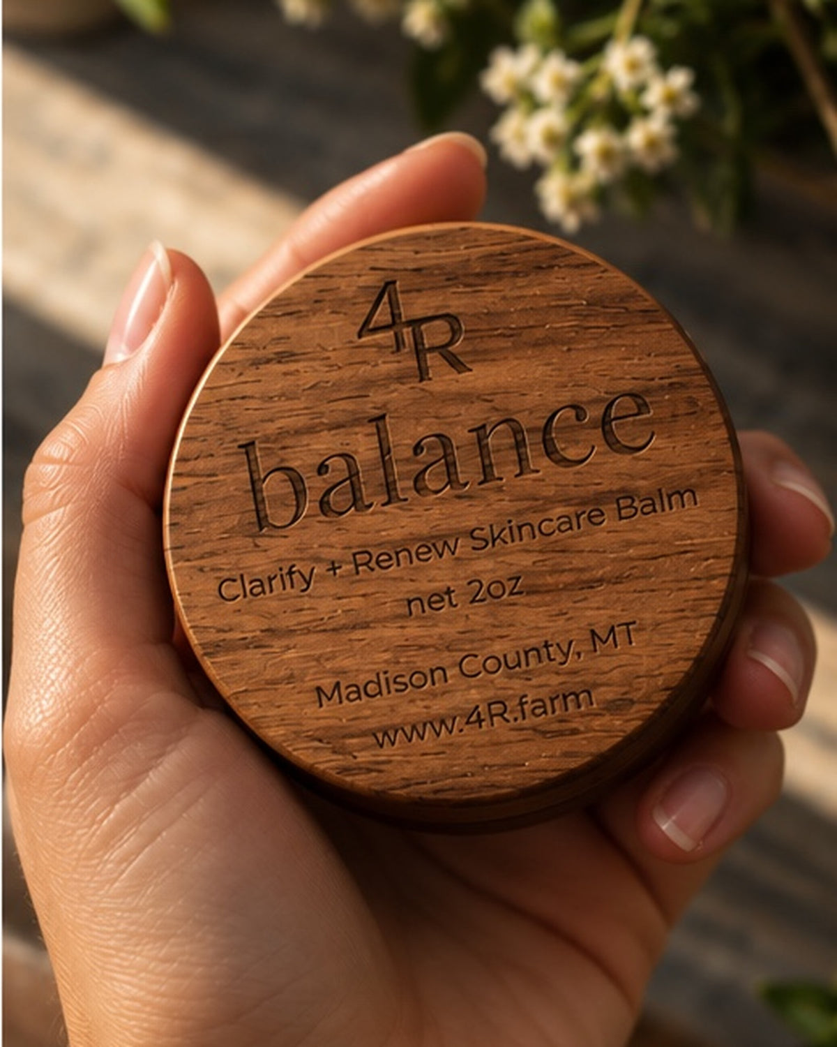 Hand holding BALANCE Clarify + Renew Skincare Balm in its walnut container.