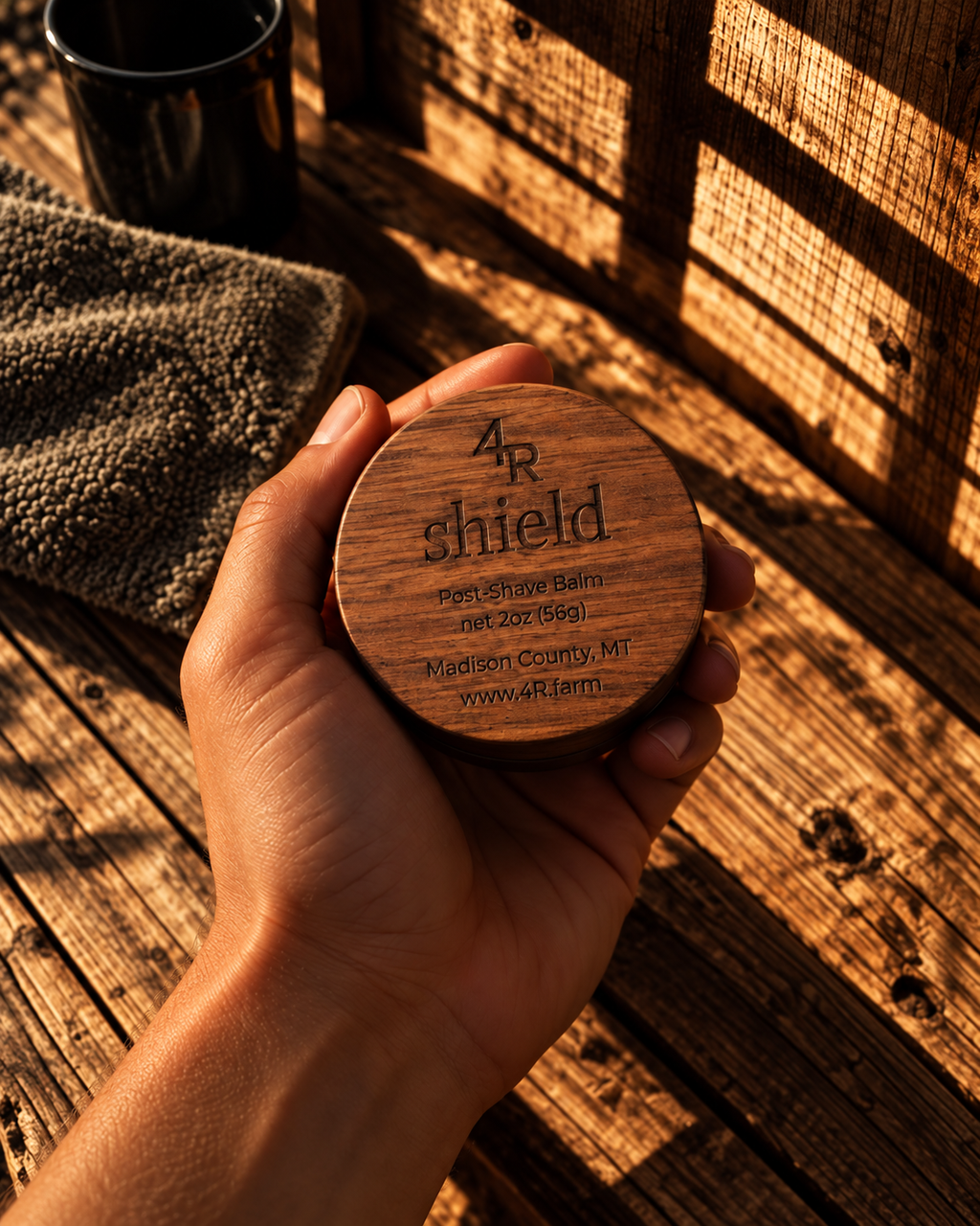 Hand holding SHIELD Post-Shave Balm in its walnut container.