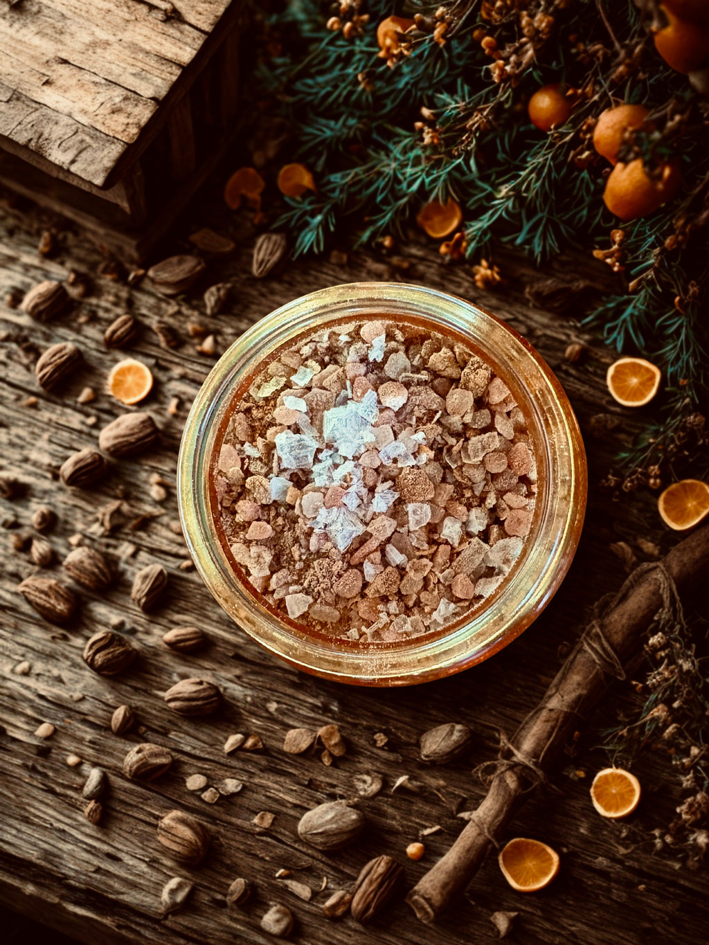 Jar of spices and salts on a wooden surface with herbs and oranges