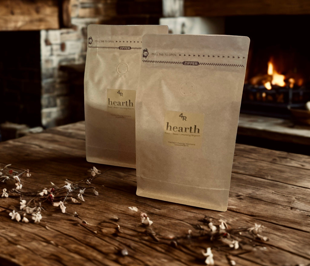 Two 'hearth' coffee bags on a wooden surface with a fireplace in the background