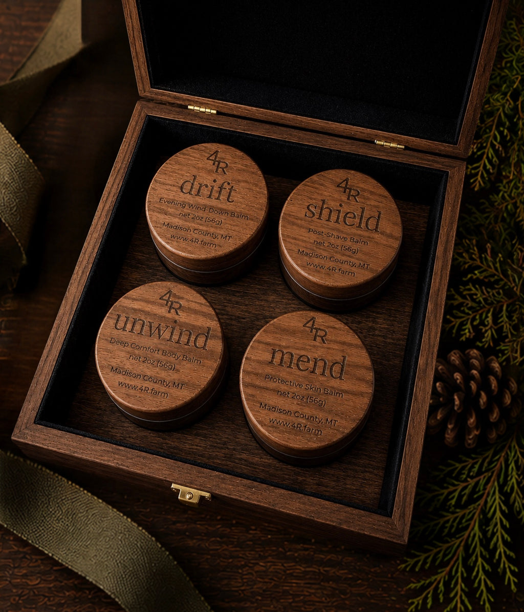Open walnut gift box holding four 4R Farm Signature balms—DRIFT, SHIELD, UNWIND, and MEND.