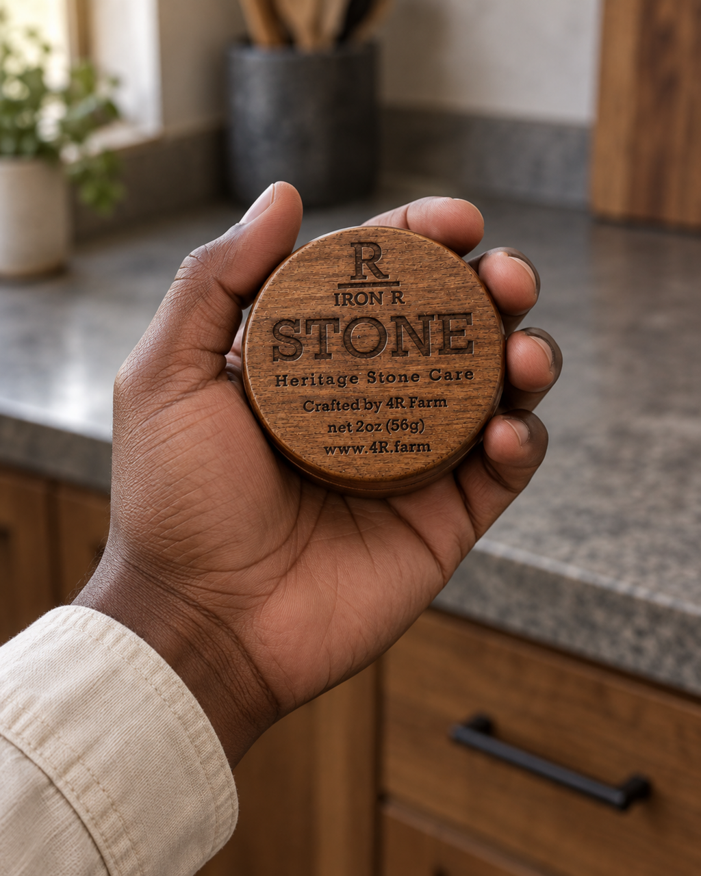 Hand holding IRON R STONE Heritage Stone Care in front of a gray stone countertop.