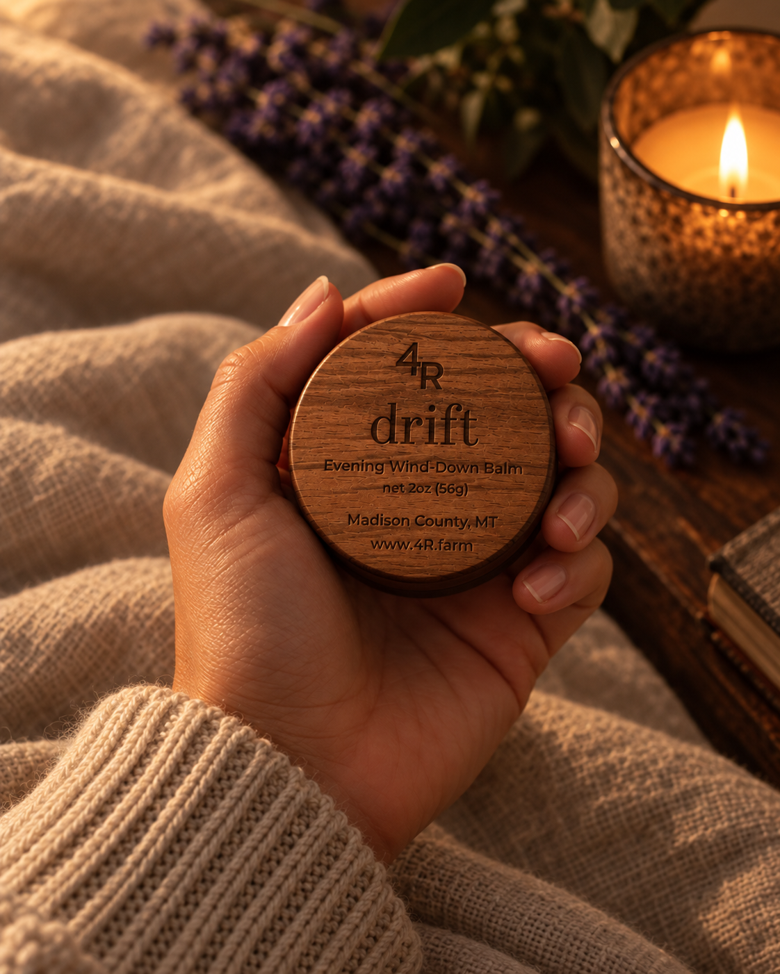 Hand holding DRIFT Evening Wind-Down Balm beside lavender and a lit candle.