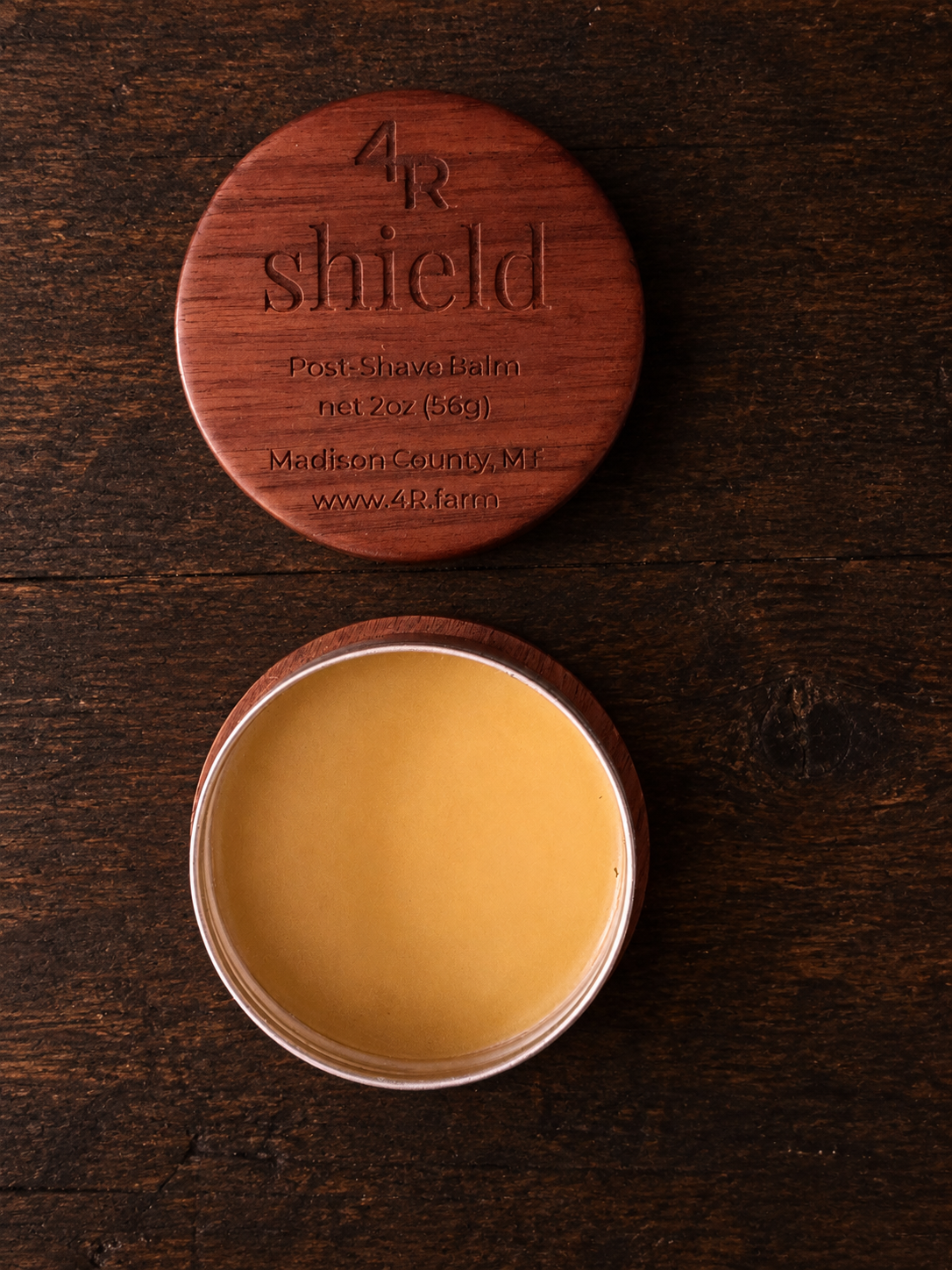 Open SHIELD Post-Shave Balm beside its engraved walnut lid.