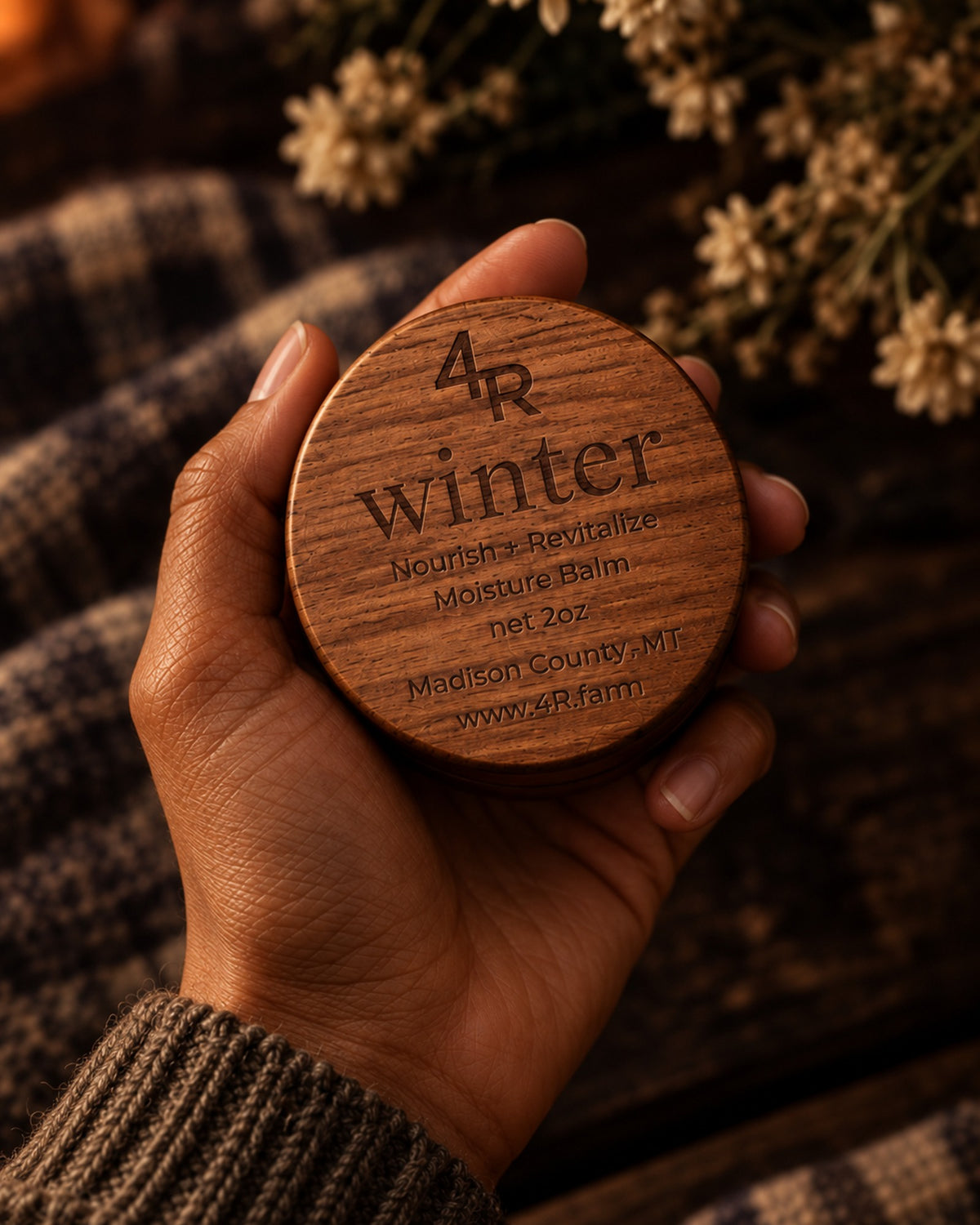 Hand holding WINTER Nourish + Revitalize Moisture Balm in its walnut container.