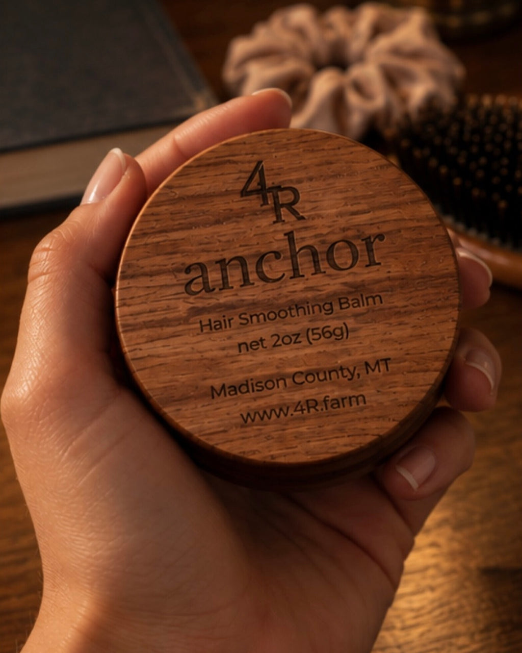 Hand holding ANCHOR Hair Smoothing Balm in its walnut container.