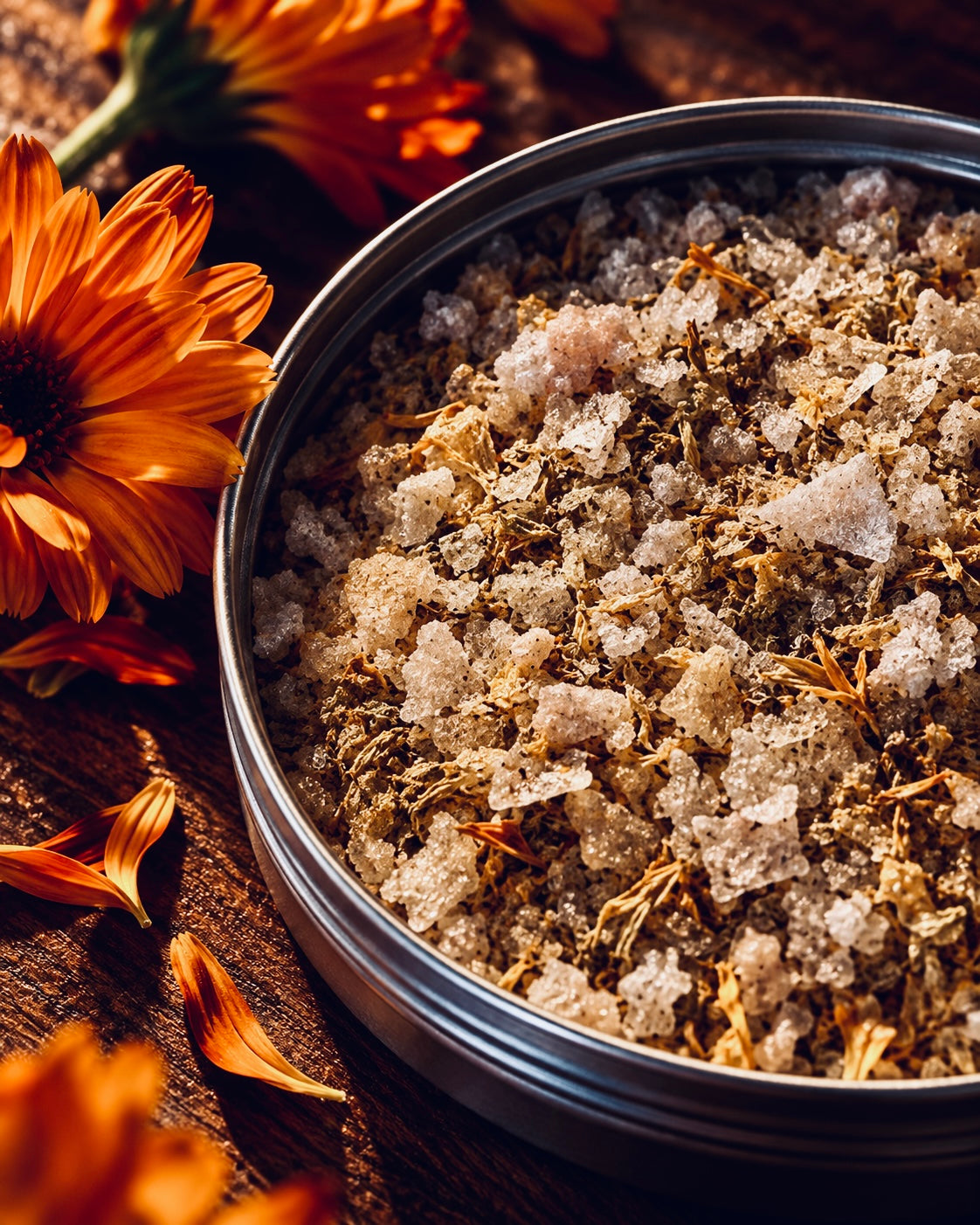 Open tin of GOLDEN salt with flaky crystals and orange flower petals.