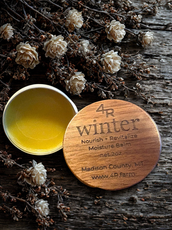Balm container with wooden lid labeled '4R winter' on a rustic wooden surface with flowers.