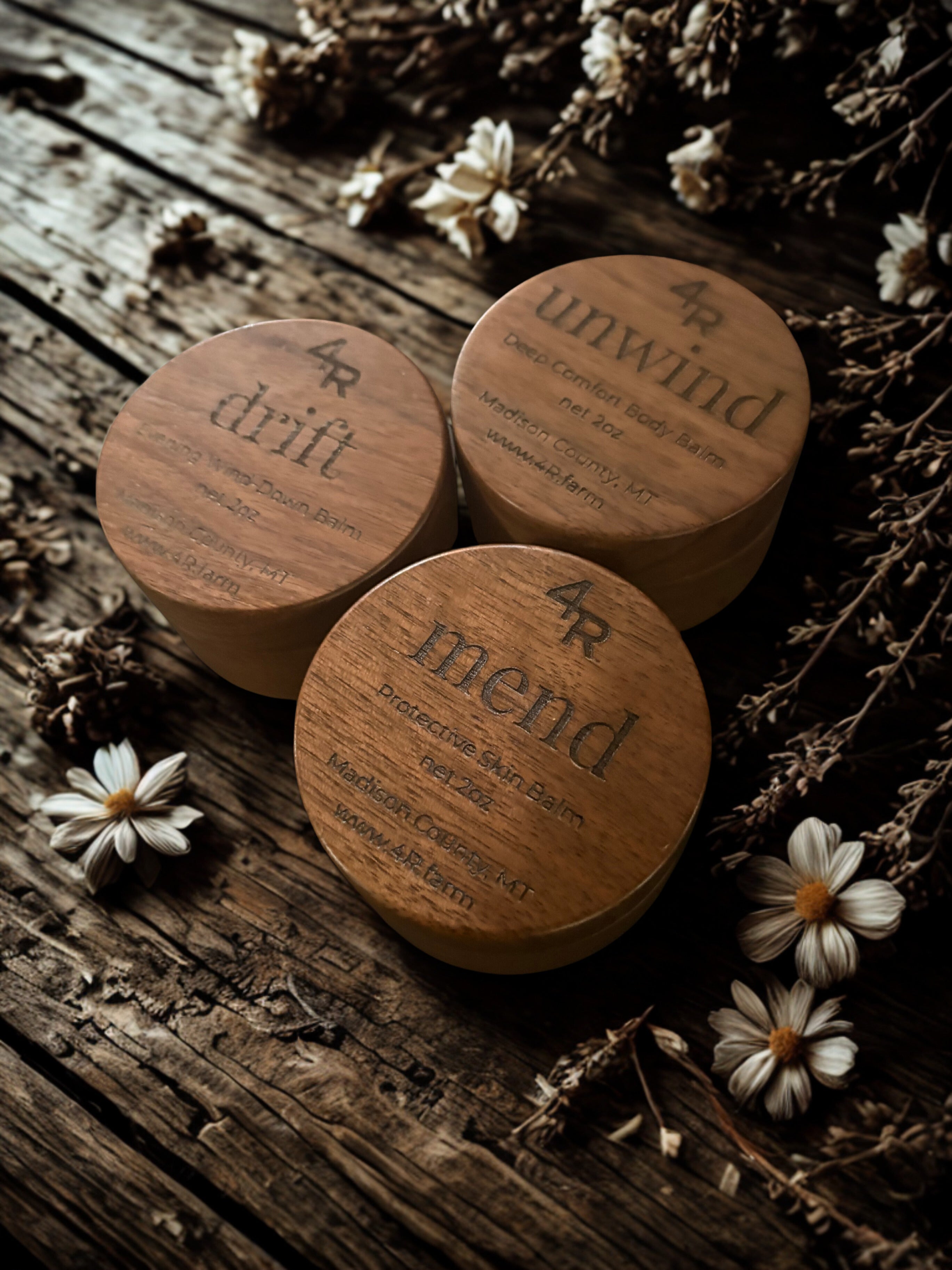 Three wooden containers labeled 'drift', 'unwind', and 'merid' on a rustic wooden surface with flowers.