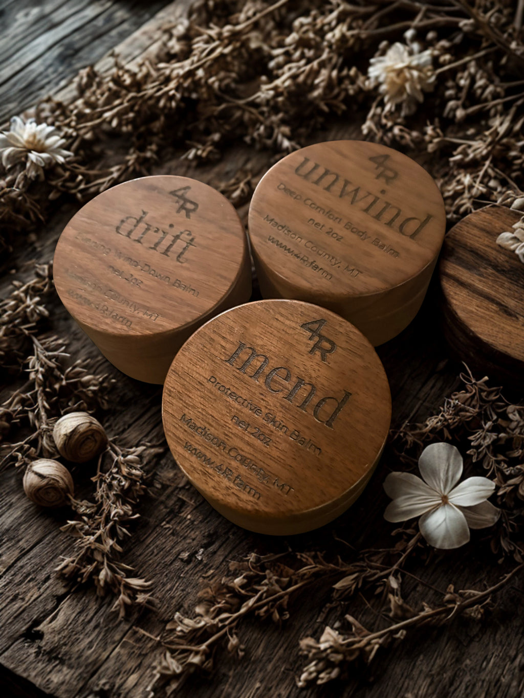 Wooden containers labeled 'drift', 'unwind', and 'mend' on a rustic wooden surface with flowers and nuts.