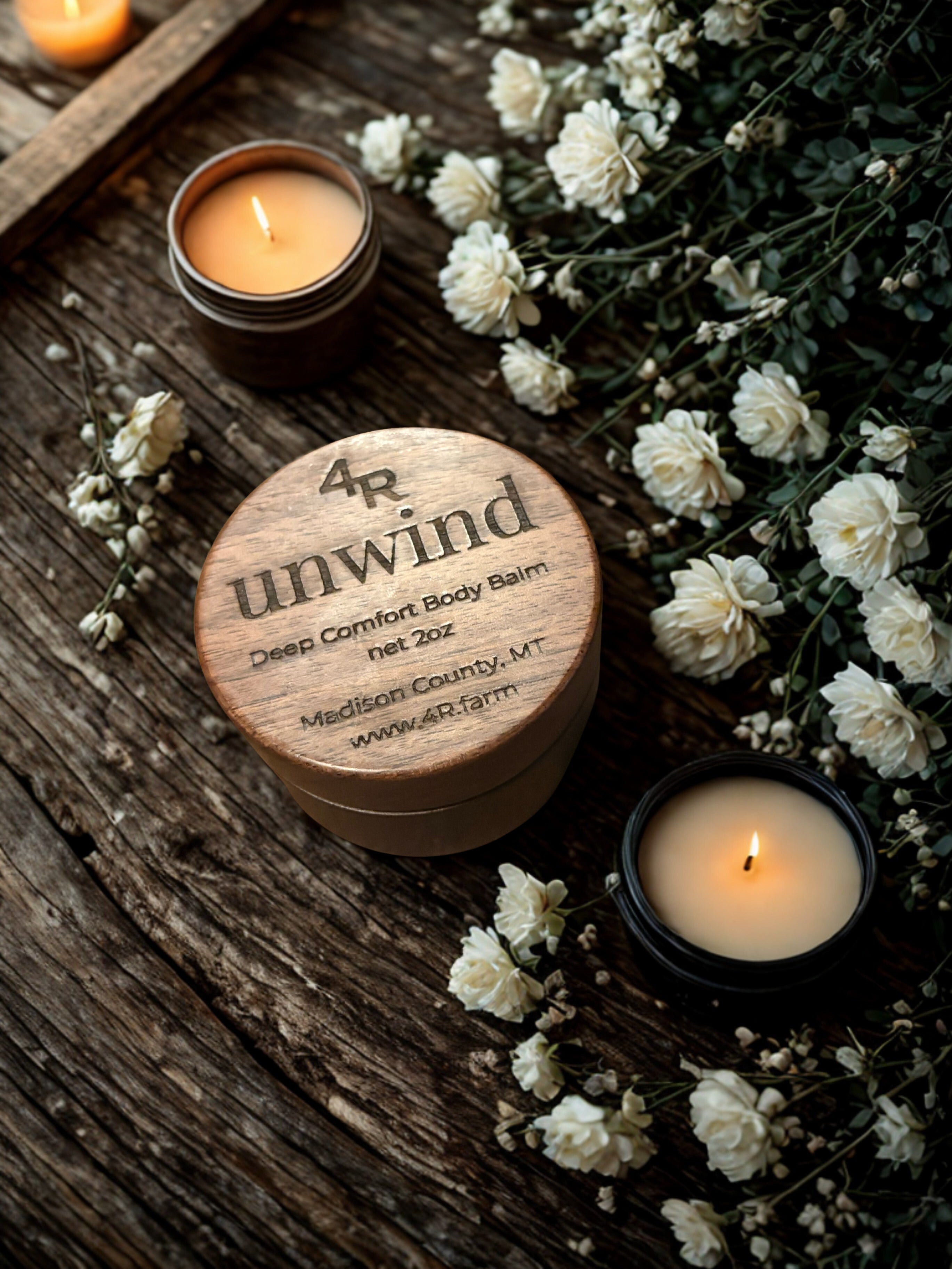 Wooden container labeled '4R unwind' with candles and flowers on a wooden surface
