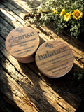 Two wooden containers labeled '4R cleanse' and '4R balance' on a wooden surface with flowers in the background.