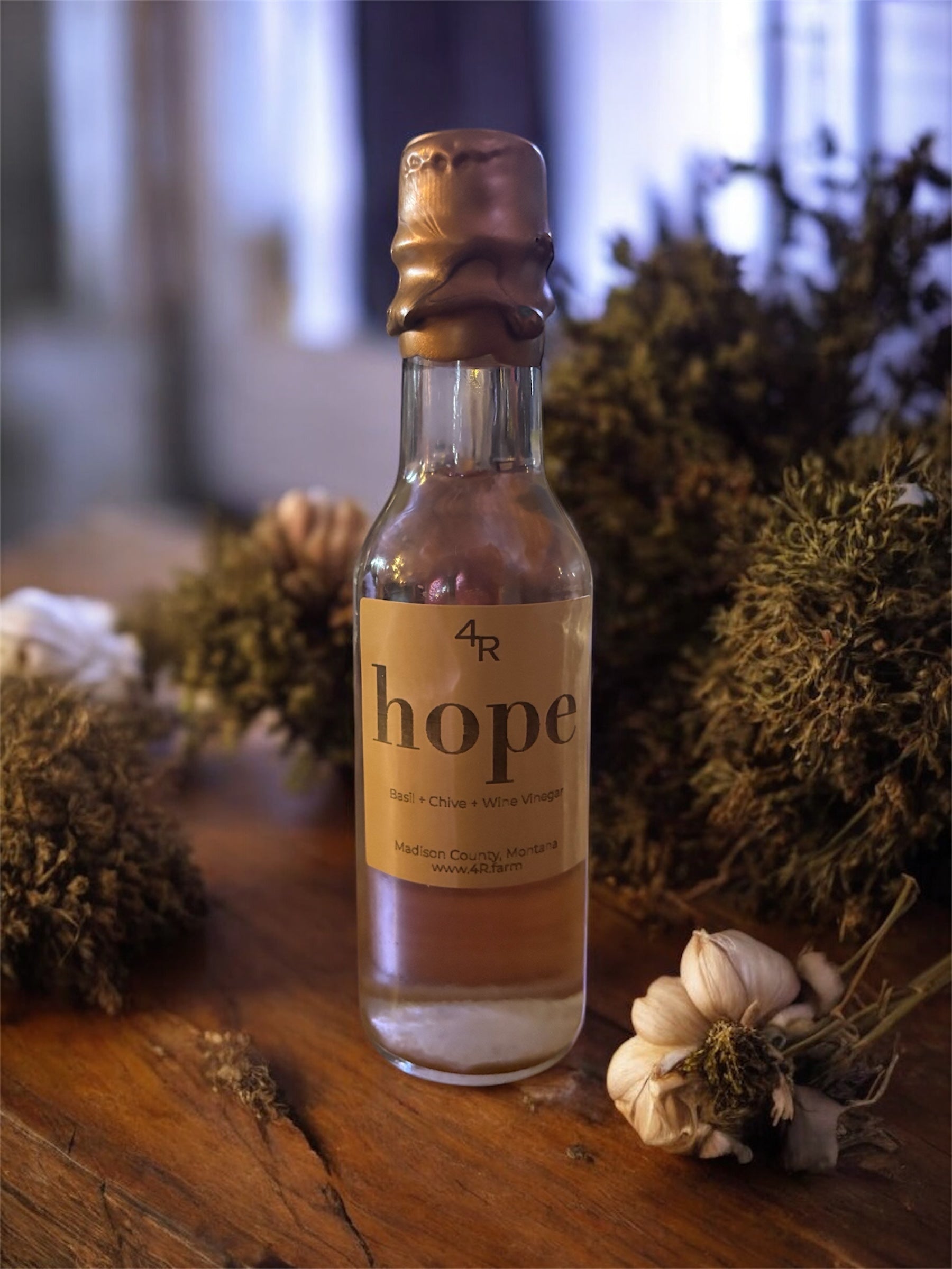 Small bottle labeled '4R hope' on a wooden surface with dried plants.