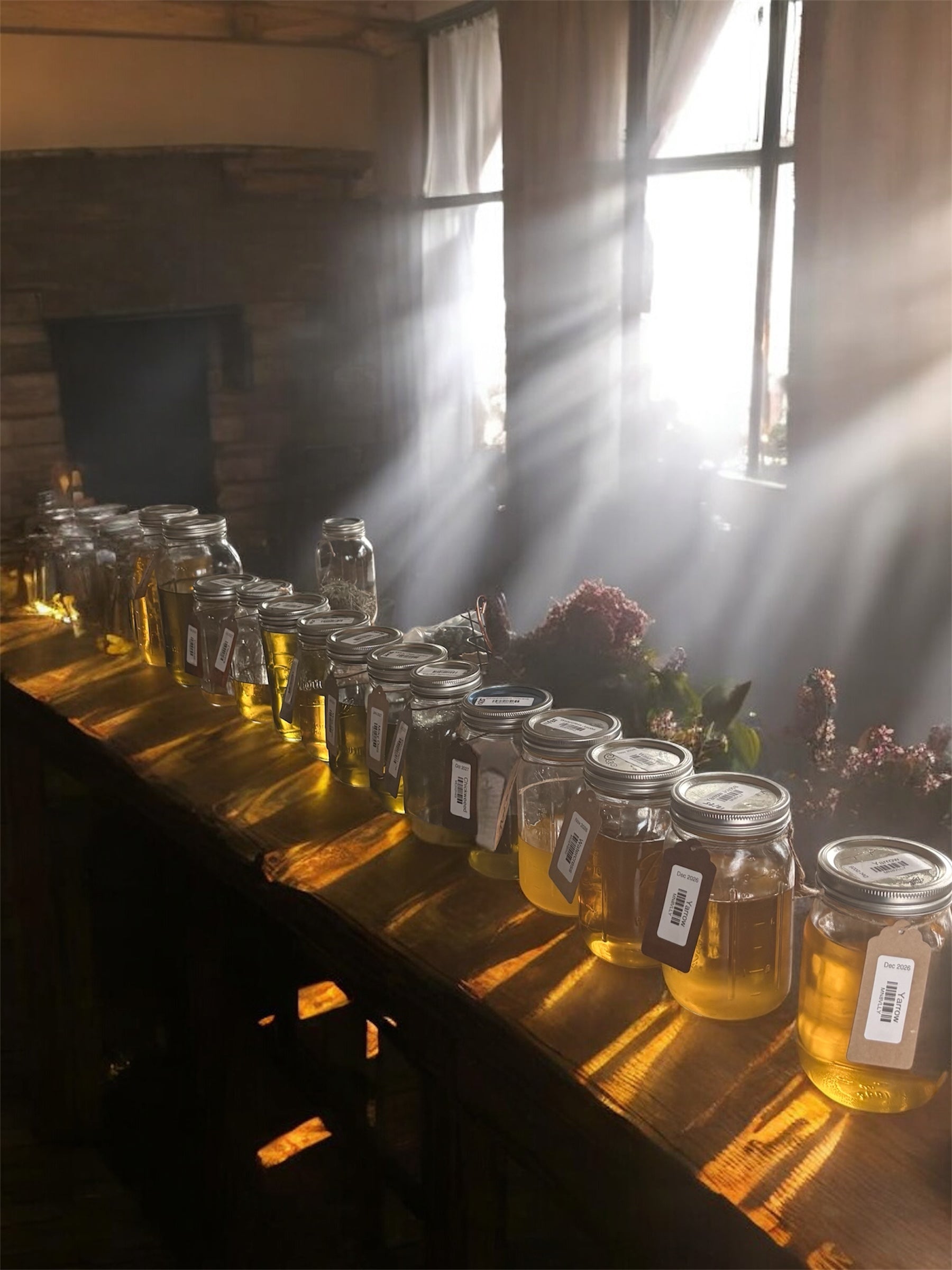 Jars of infused oils on a wooden table with sunlight streaming through a window.