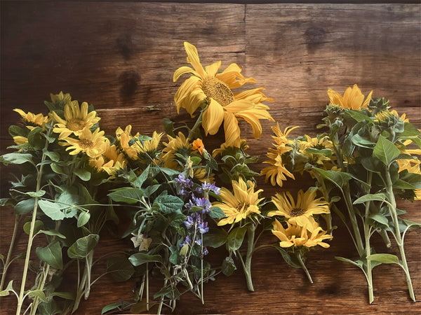 Yellow sunflowers and greenery on a wooden surface