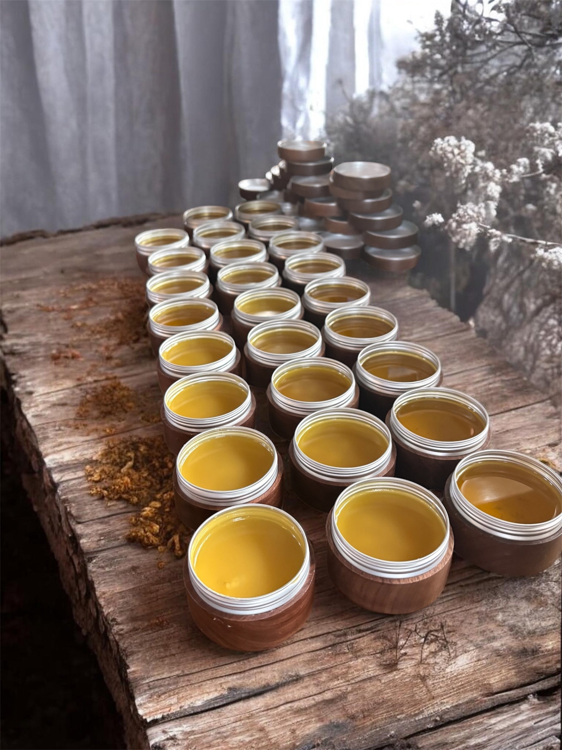 Jars of yellow colored balms on a wooden surface with a natural background