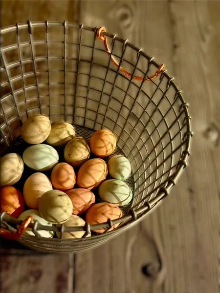 Woven basket with colorful eggs on a wooden surface